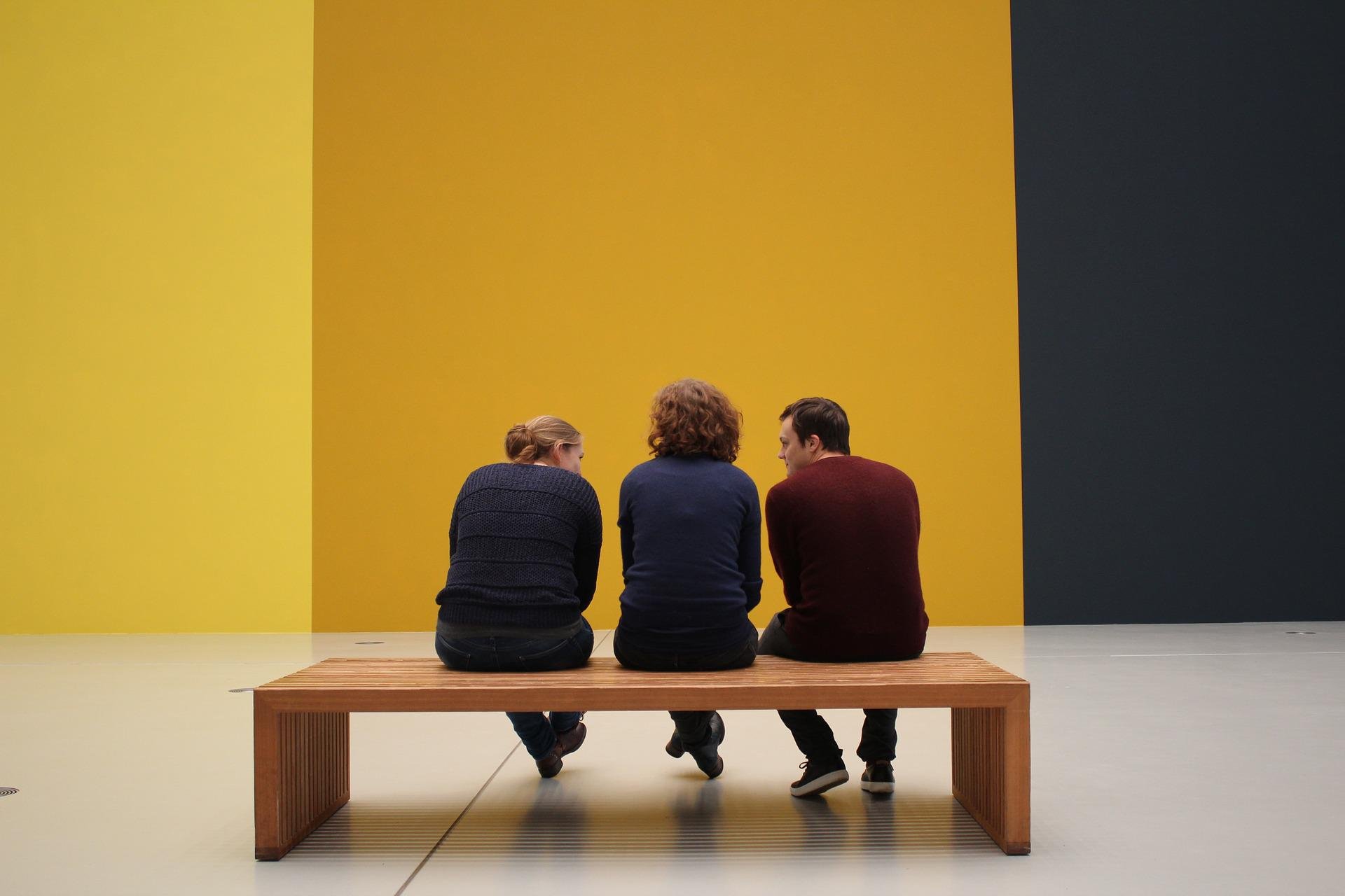Three people at a bench in an art museum