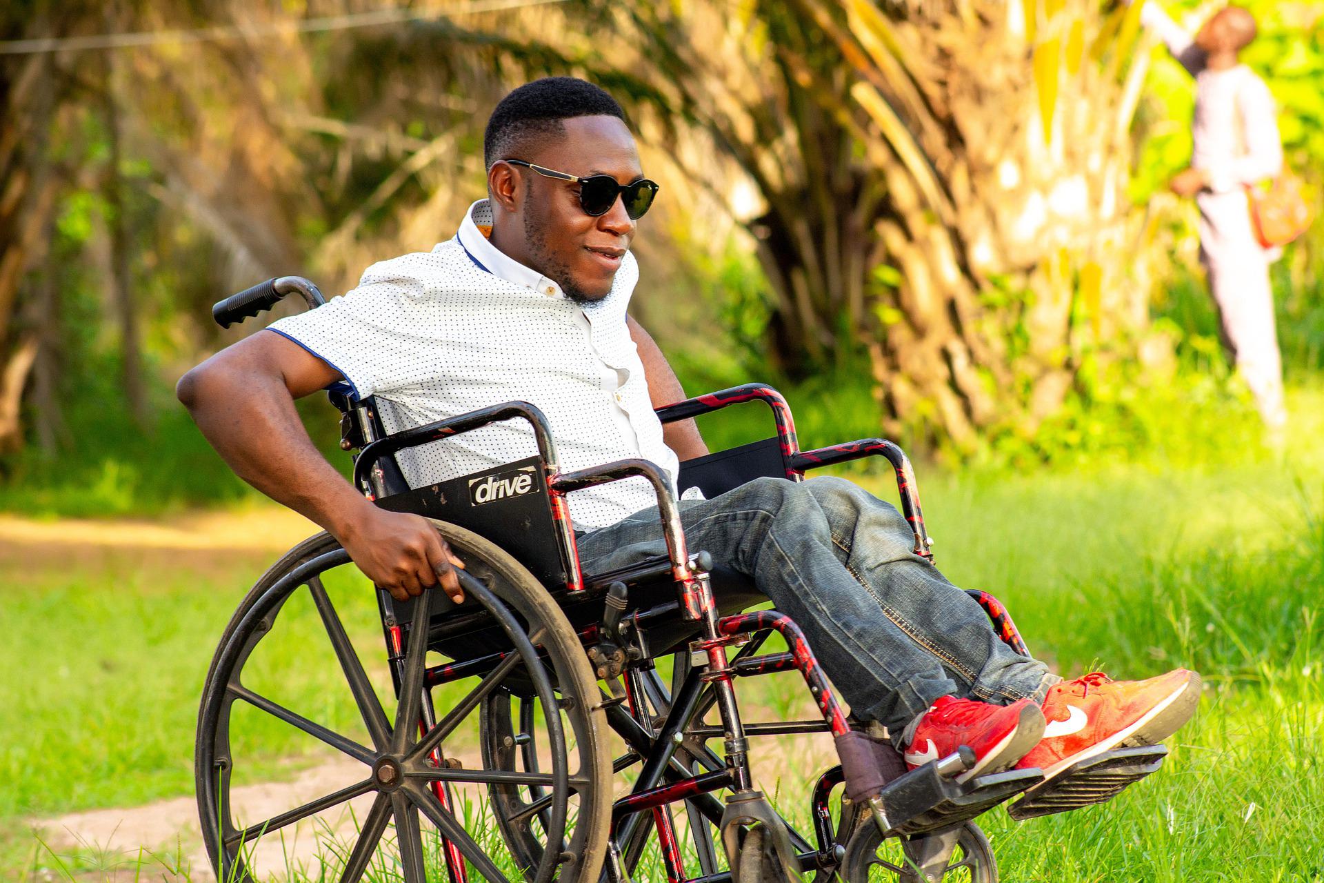 A man on wheelchair outside and wearing sunglasses