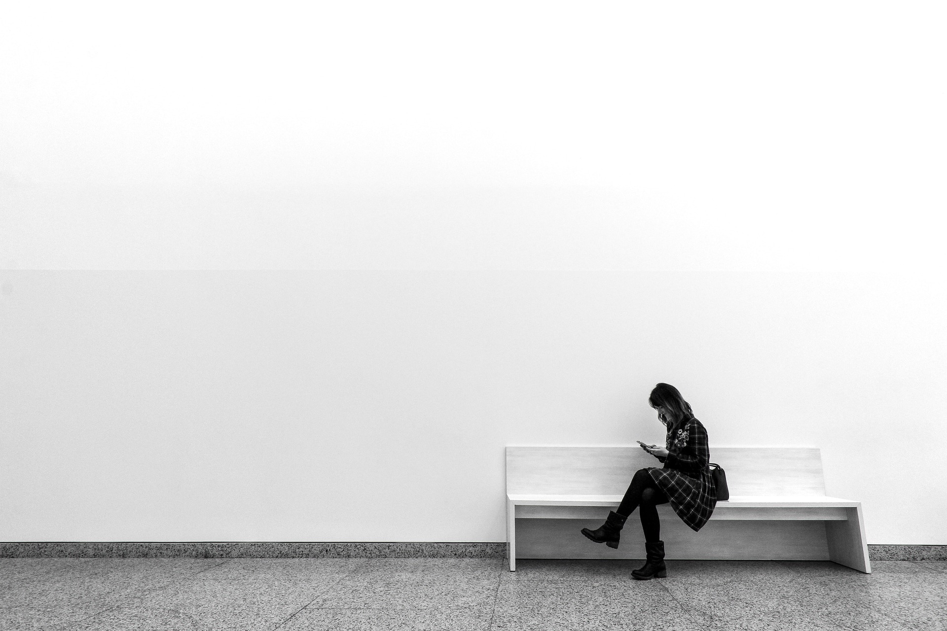 A woman sitting by a blank wall