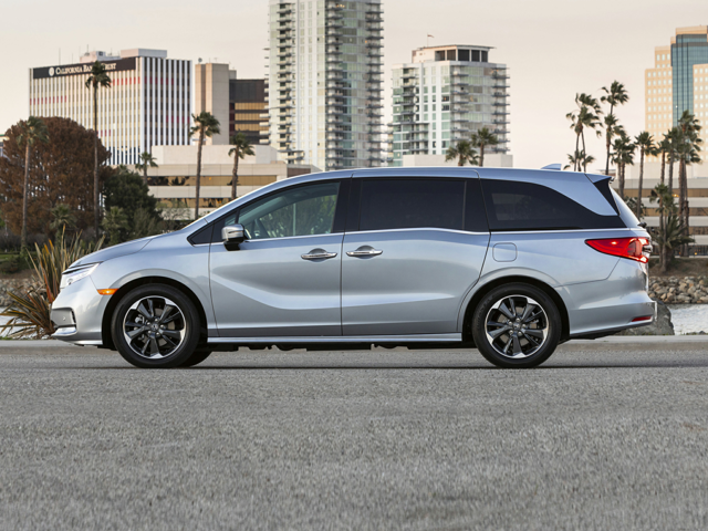 A gray Honda Odyssey Touring parked near some buildings and trees